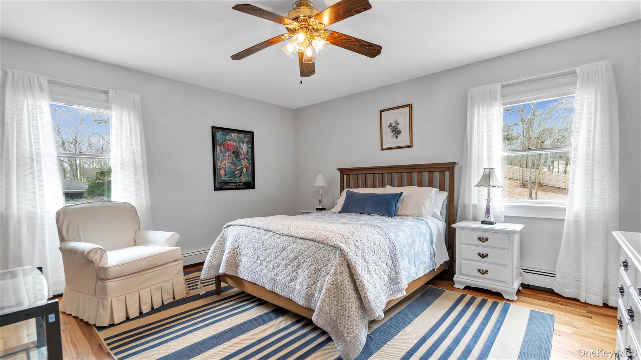 3 Debbie Trail Hampton Bays, NY 11946 - Photo 26 of 29 Bedroom featuring a baseboard radiator, multiple windows, ceiling fan, and light wood-style floors
