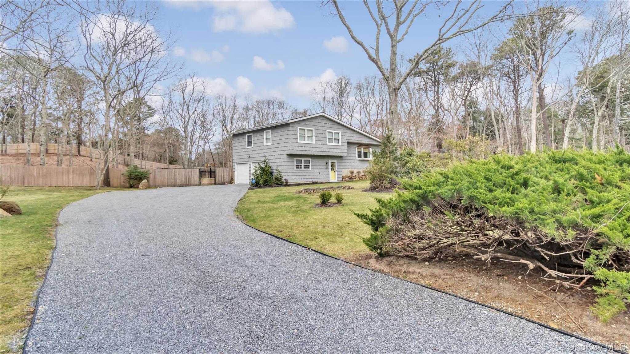 3 Debbie Trail Hampton Bays, NY 11946 - Photo 6 of 29 View of home's exterior featuring a lawn, gravel driveway, fence, and a garage