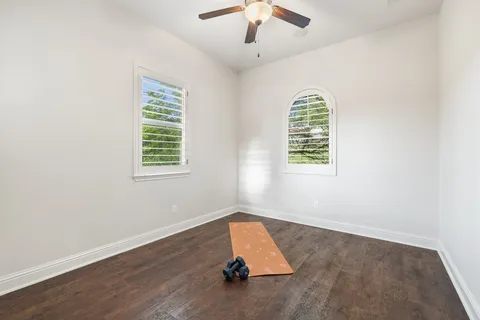 an empty room with wooden floor chandelier and windows