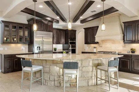a kitchen with stainless steel appliances granite countertop a stove top oven a sink a dining table and chairs