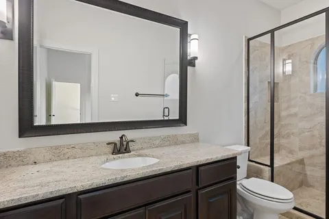 a bathroom with a granite countertop sink a toilet and a mirror