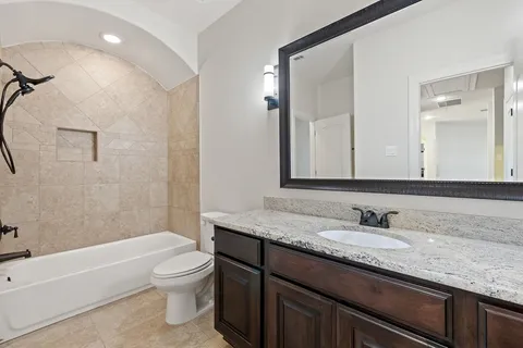 a bathroom with a granite countertop sink a toilet and bathtub
