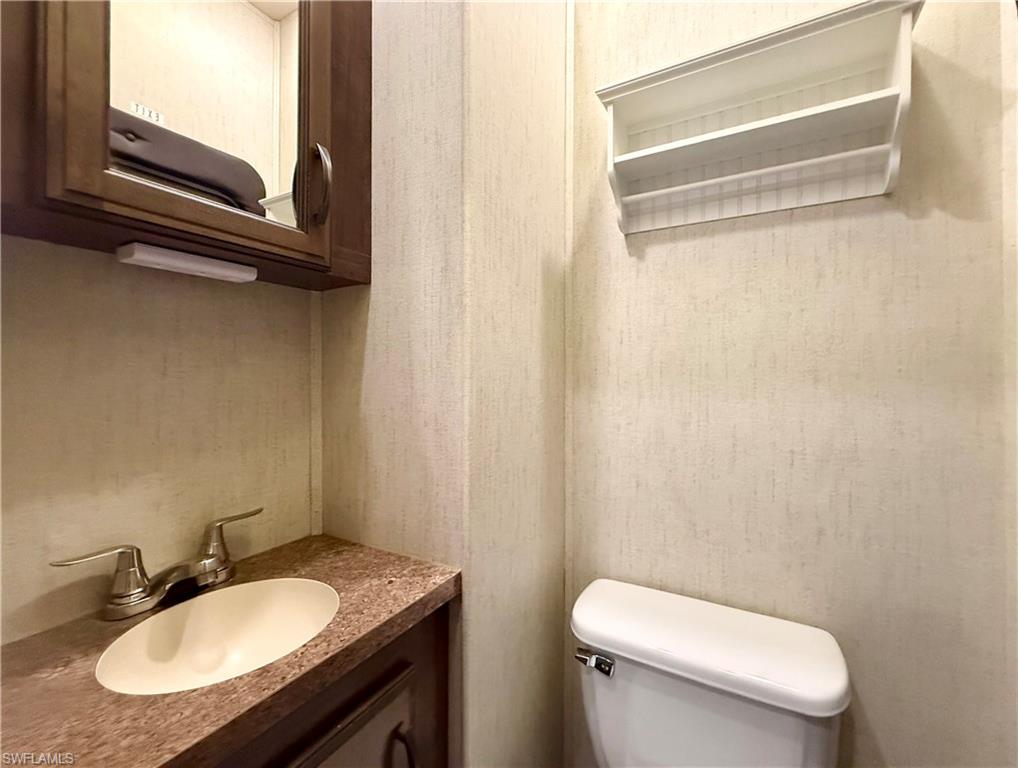 564 Cattleya Refuge, Unit 564 Naples, FL 34114 - Photo 39 of 50 a bathroom with a granite countertop toilet sink and mirror