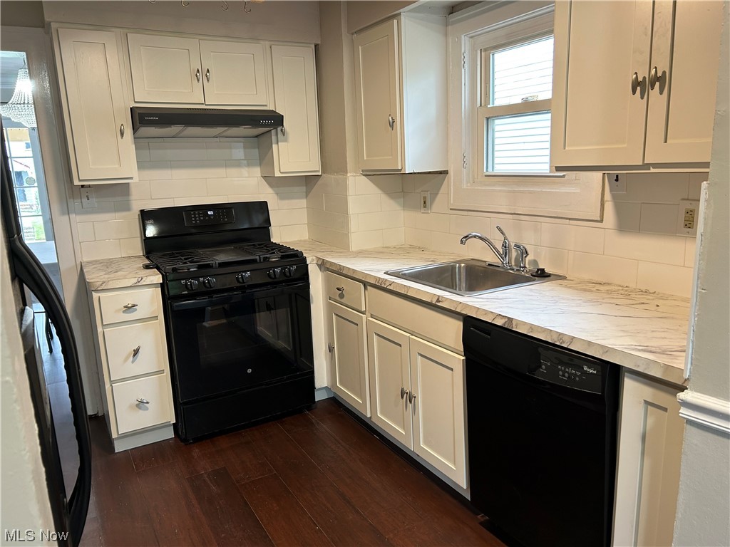 3089 Becket Road Cleveland, OH 44120 - Photo 5 of 16 Kitchen with black appliances, white cabinetry, dark hardwood flooring, light countertops, and subway tile backsplash