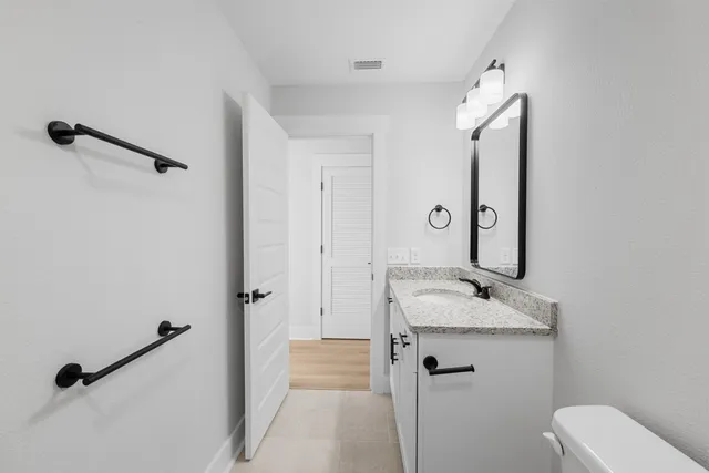 a bathroom with a granite countertop sink mirror and toilet