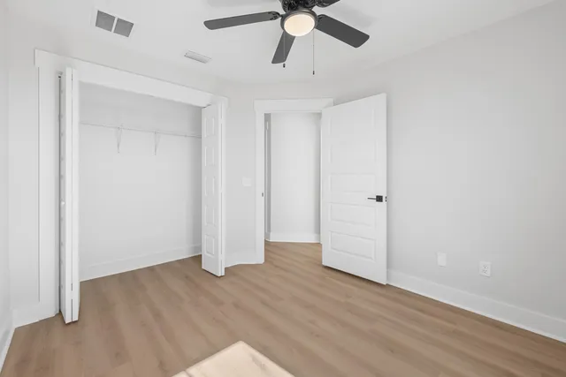 an empty room with wooden floor closet and windows