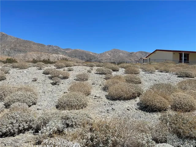 a view of a dry yard with mountains in the background