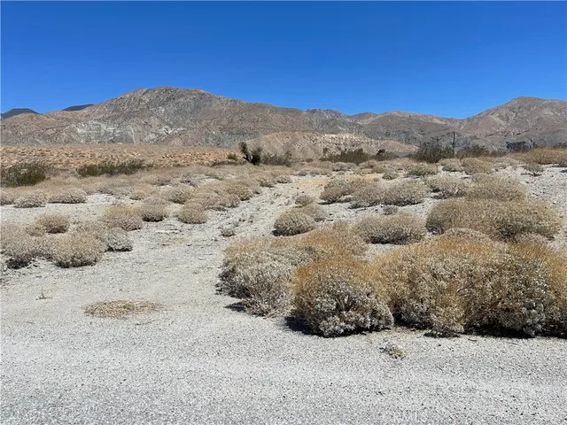 a view of a dry field with mountains in the background