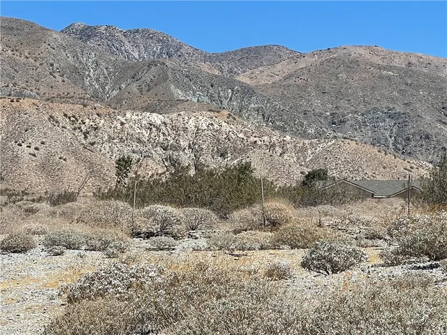 a view of a dry yard with mountains in the background