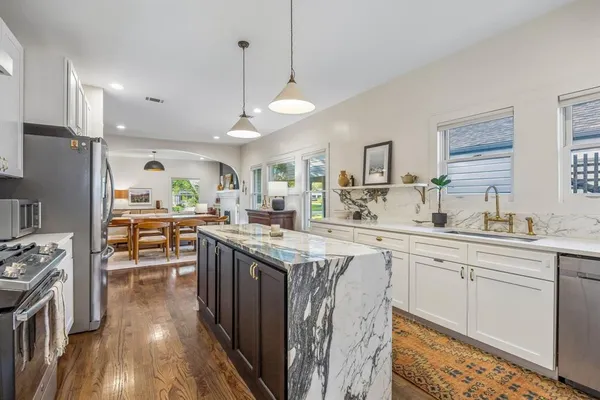 a kitchen with stainless steel appliances a stove top oven a sink a center island and cabinets