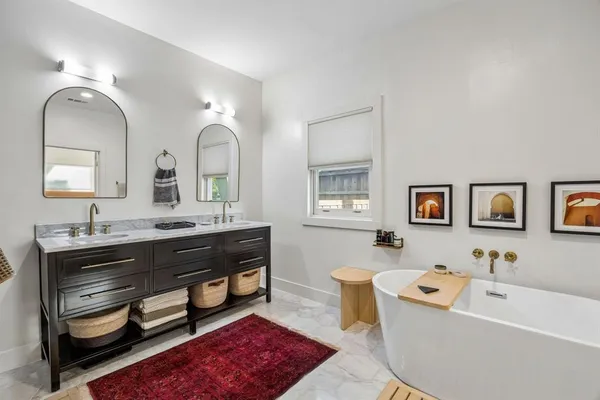 a spacious bathroom with double vanity sinks a large mirror and a bathtub