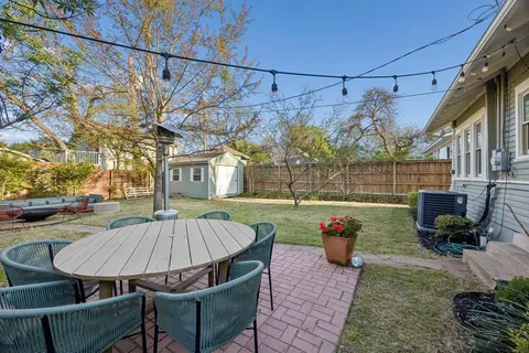 a view of a patio with table and chairs potted plants and large tree