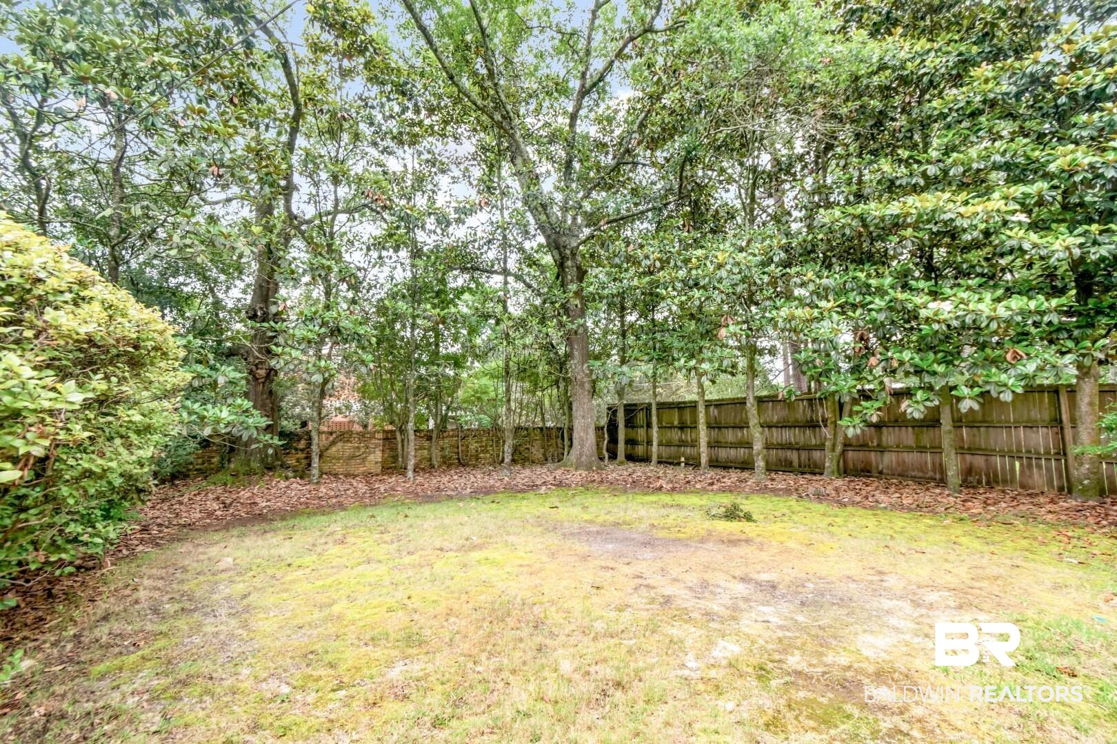 4776 Falls Church Road Mobile, AL 36608 - Photo 36 of 45 Rear yard featuring a wood privacy fence, mature trees, and natural landscaping