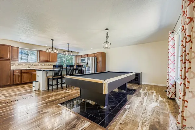 a kitchen with a stove a refrigerator and a dining table with wooden floor