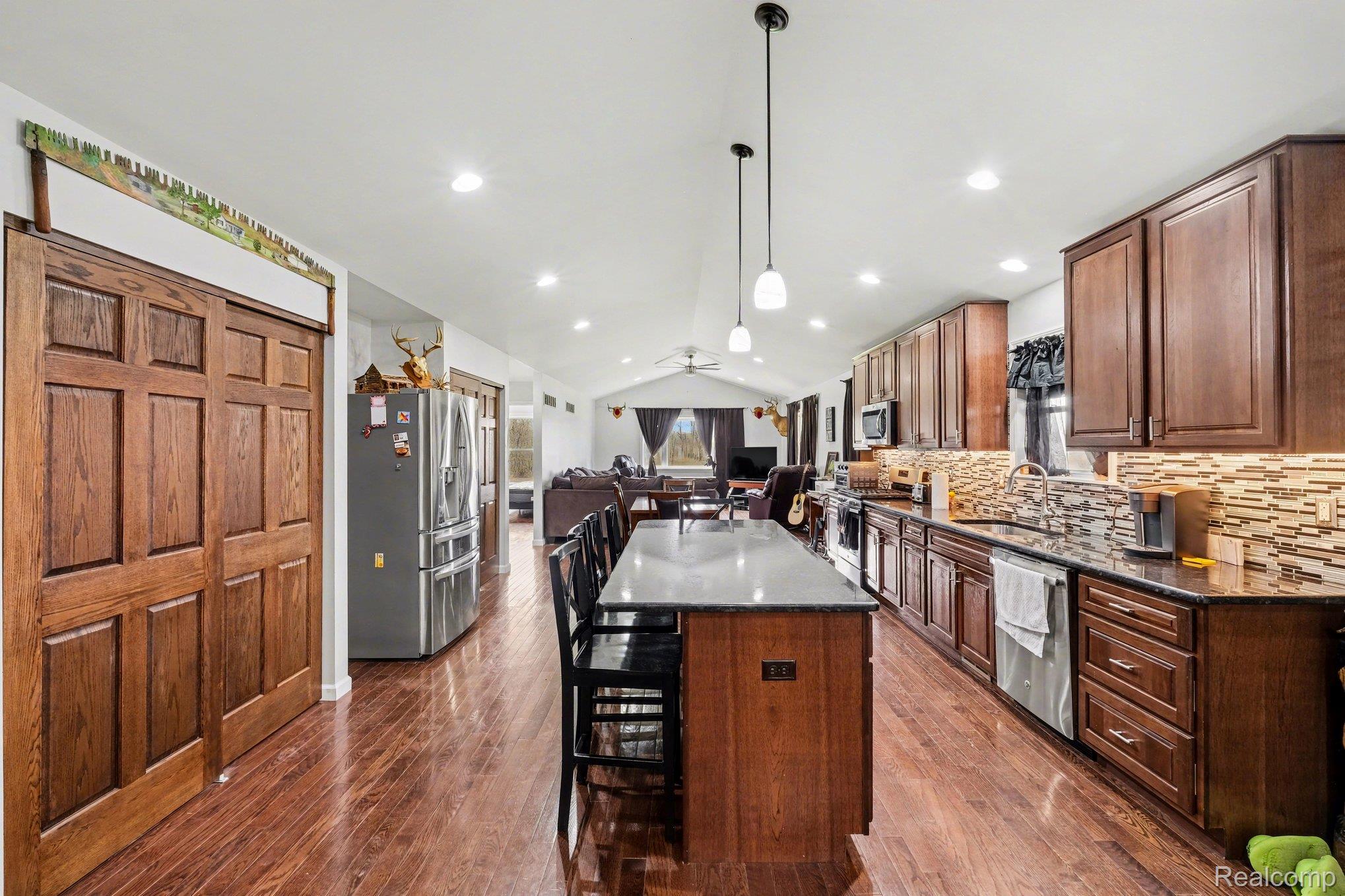 2800 Meadowdale Road Metamora, MI 48455 - Photo 28 of 28 Kitchen featuring vaulted ceiling, stainless steel appliances, open floor plan, dark stone countertops, and a center island