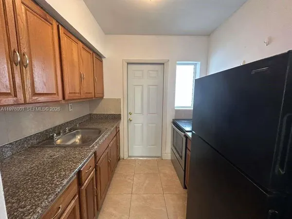 a kitchen with granite countertop a refrigerator and a sink