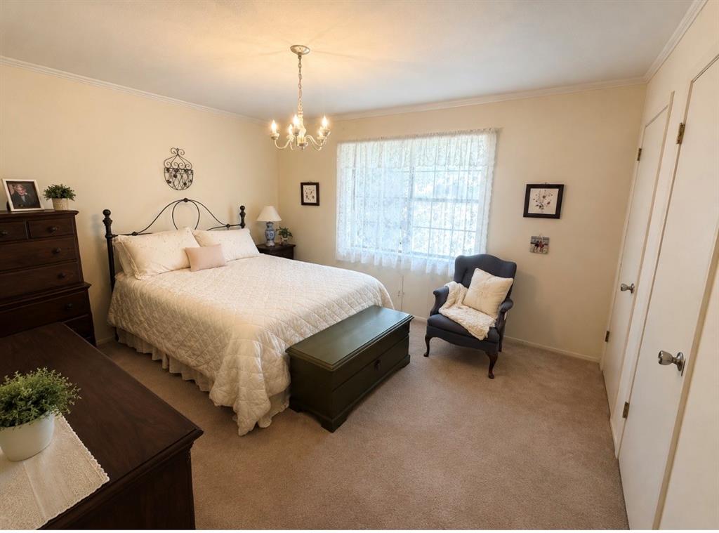803 Spring Street Springhill, LA 71075 - Photo 6 of 9 Carpeted flooring, window with sheer curtains, traditional chandelier, and two white doors with brass hardware