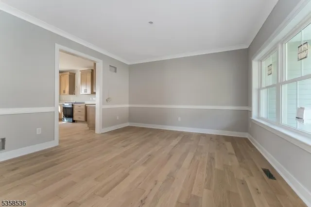 a view of empty room with wooden floor and windows