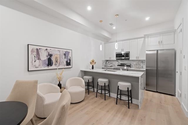 491 Broadway, Unit 202 Bayonne, NJ 07002 - Photo 4 of 20 a kitchen with stainless steel appliances granite countertop a white refrigerator a microwave a sink and white cabinets