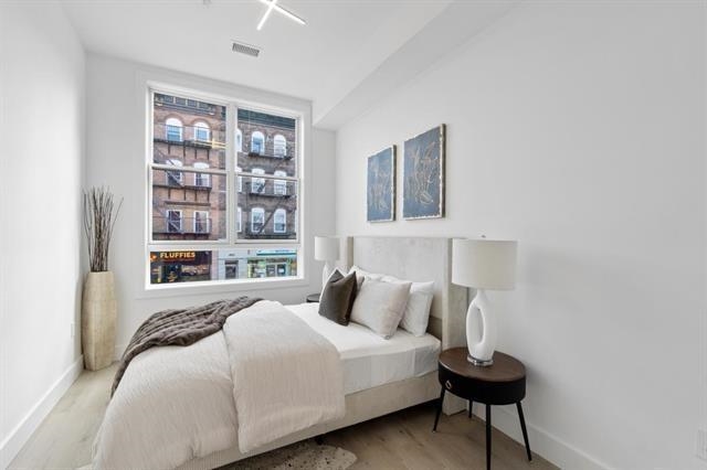 491 Broadway, Unit 202 Bayonne, NJ 07002 - Photo 7 of 20 a bedroom with bed and wooden floor