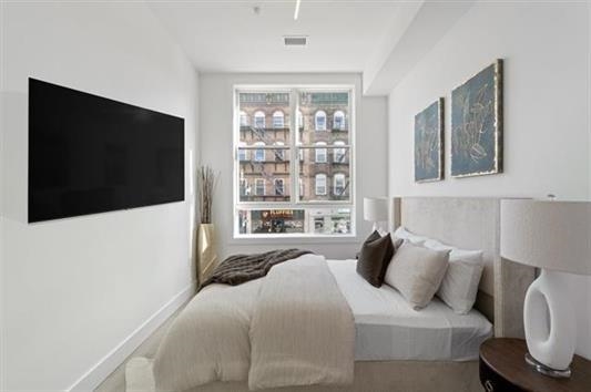 491 Broadway, Unit 202 Bayonne, NJ 07002 - Photo 10 of 20 a bedroom with a bed and a flat screen tv