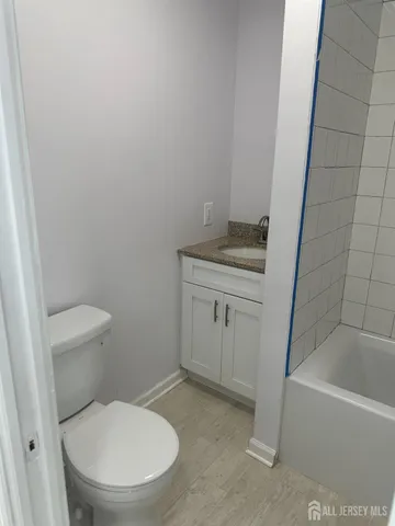 a bathroom with a granite countertop toilet and a bathtub