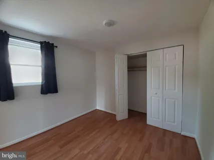 a view of an empty room with wooden floor and closet