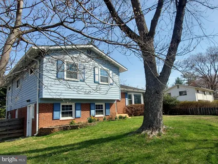 a view of a brick house with a big yard large tree and a large window