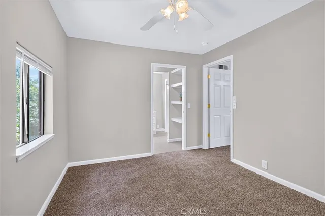 an empty room with windows and chandelier fan