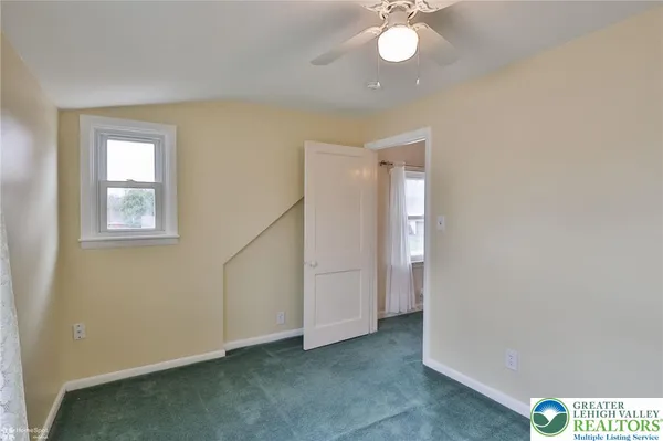 a view of an empty room with window and chandelier fan