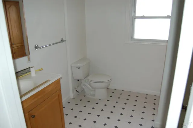 a bathroom with a sink a toilet a window and vanity