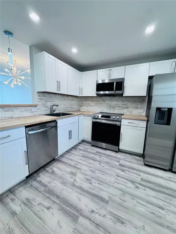 a large kitchen with stainless steel appliances granite countertop a stove a sink and a microwave