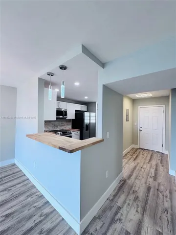 a view of kitchen with kitchen island wooden floor and stainless steel appliances