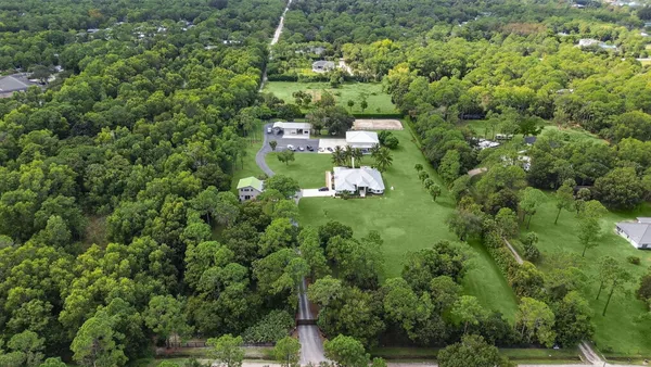 a view of a house with a lush green forest