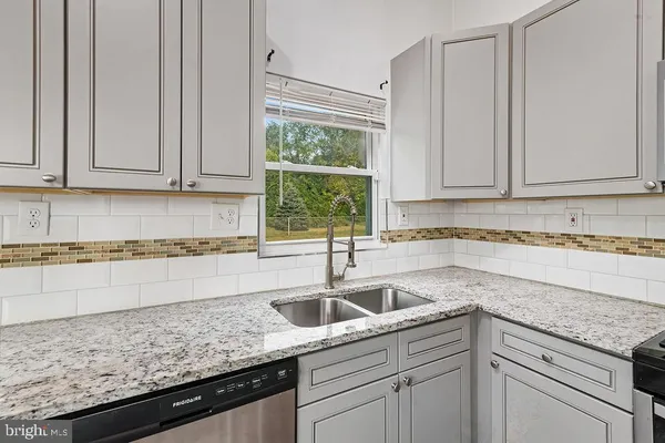 a kitchen with granite countertop a sink window and cabinets