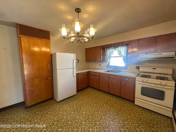 a kitchen with stainless steel appliances granite countertop a refrigerator a sink dishwasher a stove with white cabinets and wooden floor