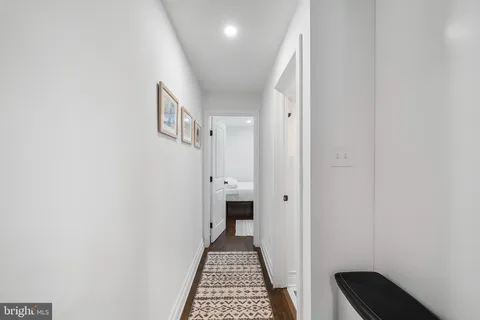 a view of a hallway with wooden floor and a bathroom