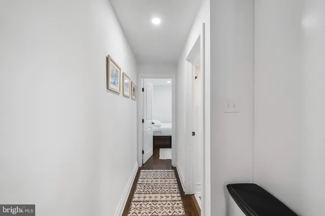 a view of a hallway with wooden floor and a bathroom