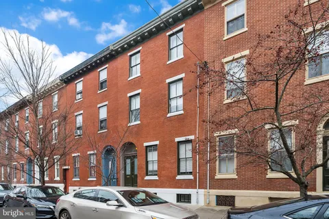 a front view of a building with lot of cars and trees