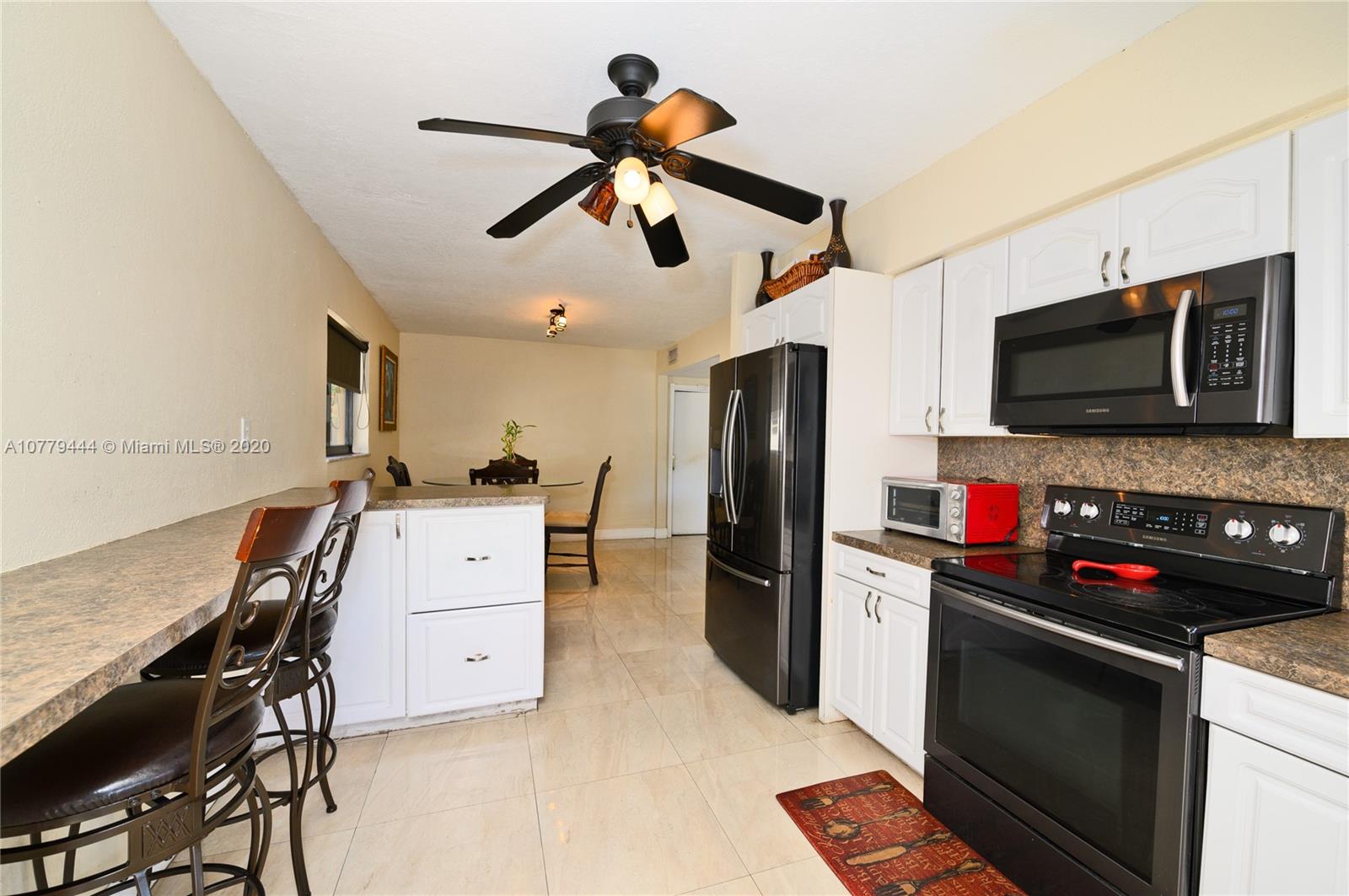 3816 East Lake Road Miramar, FL 33023 - Photo 8 of 25 a kitchen with stainless steel appliances kitchen island a stove a sink dishwasher a refrigerator with a dining table and chairs