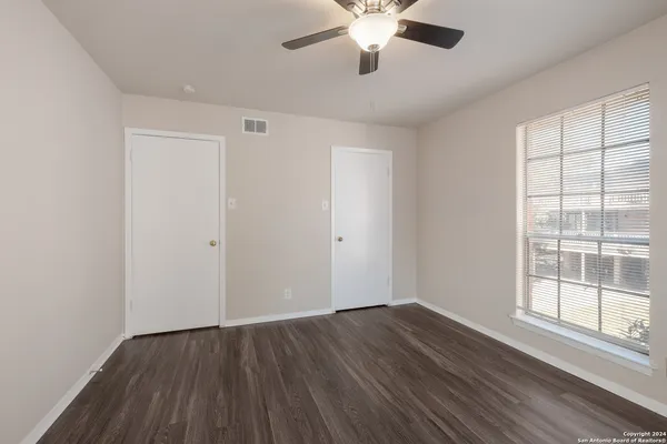 an empty room with wooden floor and windows