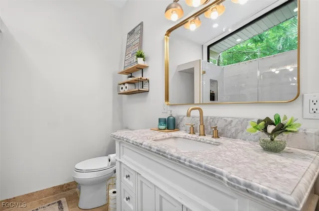 a bathroom with a granite countertop sink a toilet and a mirror