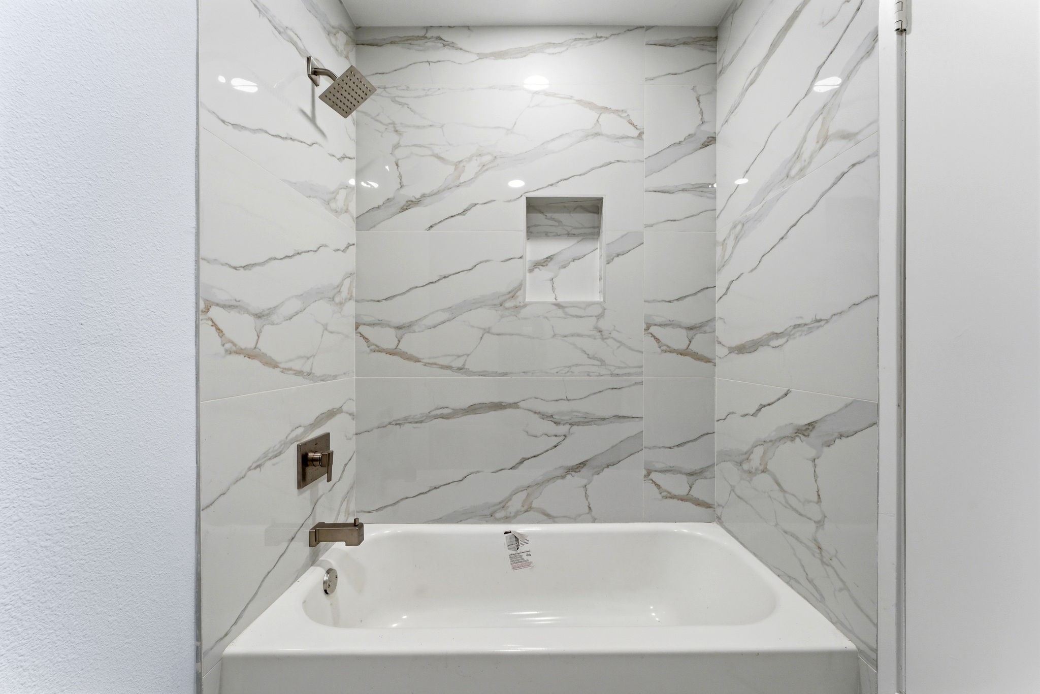 910 Beaver Bend Road Houston, TX 77088 - Photo 23 of 48 Step into a spa-inspired bath where stunning marble-style tile and modern fixtures turn everyday routines into moments of relaxation.