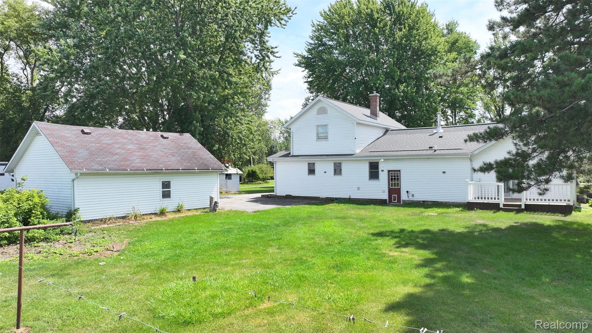 12930 Wilkinson Road Freeland, MI 48623 - Photo 10 of 76 Expansive lawn with a detached auxiliary building, multi-level home exterior, and a rear deck