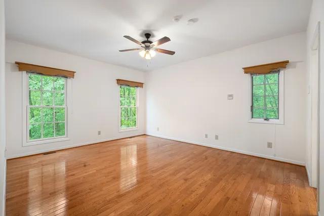 a view of an empty room with window and wooden floor