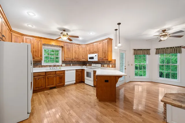 a view of a livingroom with a chandelier fan and kitchen view