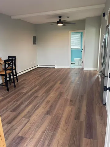 an empty room with wooden floor chandelier fan and windows