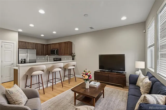 a living room with furniture kitchen view and a wooden floor