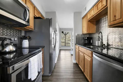 a kitchen with stainless steel appliances granite countertop a stove a sink and a microwave
