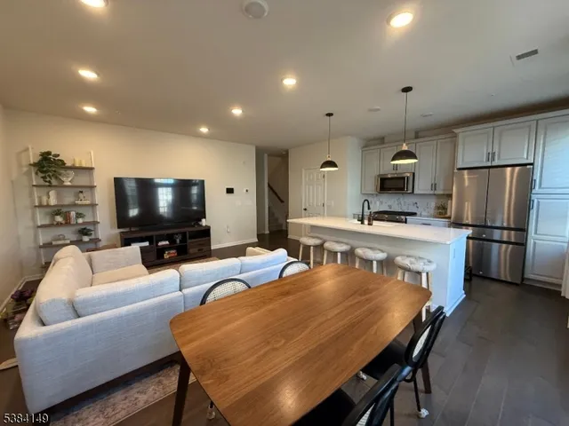 a living room with stainless steel appliances furniture a flat screen tv and kitchen view